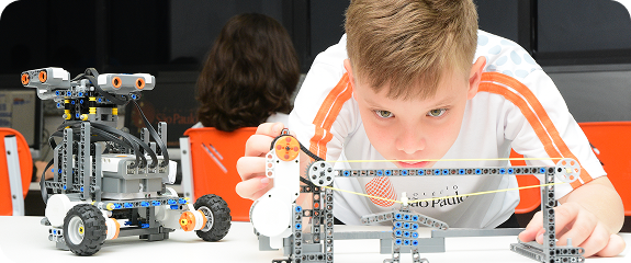Criança concentrada brincando com peças de robótica e Lego