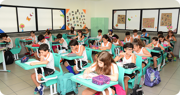 Sala de aula do Colégio São Paulo com várias crianças em carteiras verdes fazendo atividades