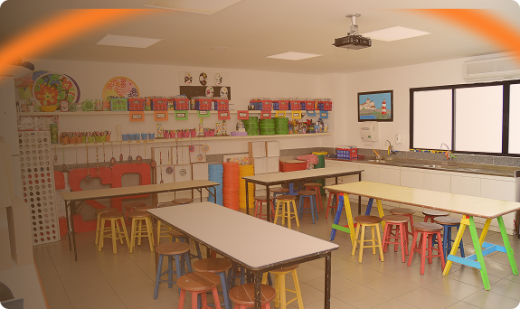 Sala de atividades colorida do Colégio São Paulo com bancos e mesas de diversas cores e prateleiras com materiais escolares